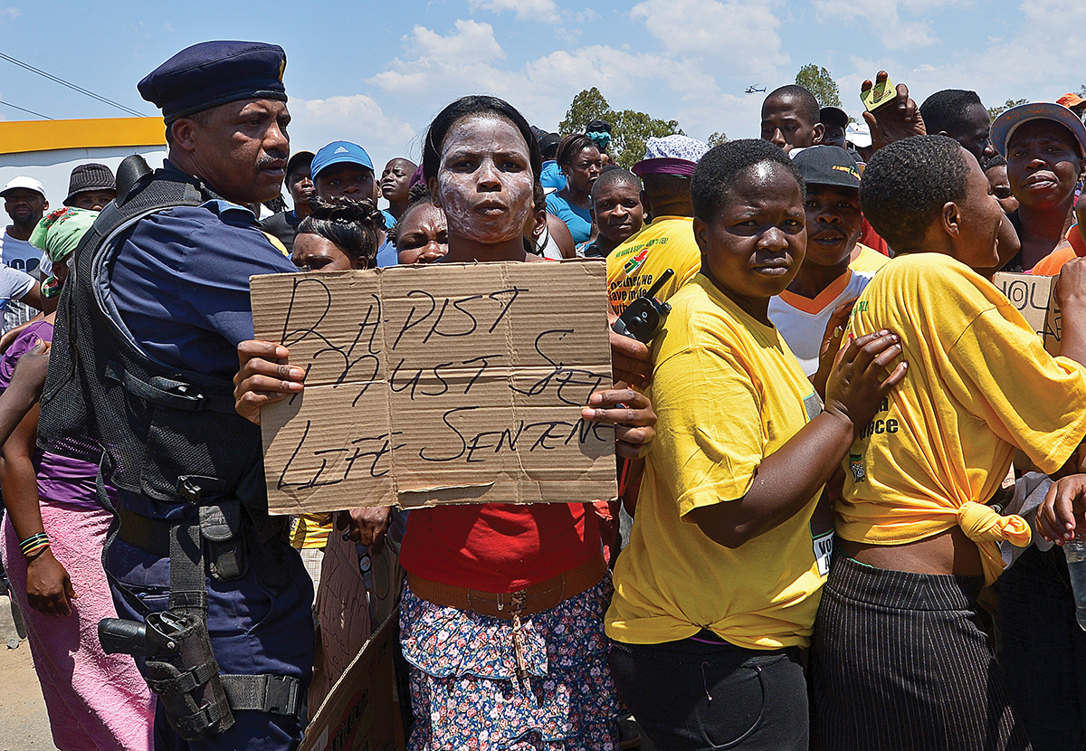 A protester holds on October 18, 2013 a placard reading "Rapist must get Life Sentence" during a demonstrating in Diepsloot, north of Johannesburg